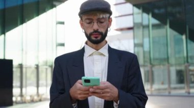 Resmi takım elbiseli, gözlüklü, iş yerinde cep telefonu kullanan, ciddi görünümlü beyaz bir hippi iş adamı. Profesyonel ticari erkek, ofis binasının dışındaki hücrede mesajlaşıyor.