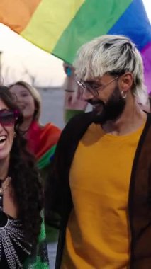 Dikey Genç LGBT cemaati neşeli çeşitli arkadaşlar eşcinsellerin geçit töreninde birlikte dolaşıyorlar. Mutlu gökkuşağı renkli insanlar gülümsemeyi seviyorlar, kucaklaşmayı dışarıda yürümeyi. Gen z ve cinsel özgürlük