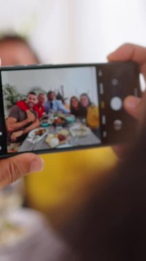 Kafkasyalı bir adamın kafkas aile toplantısının fotoğraflarını çektiği dikey POV akıllı telefonu içeride birlikte kutluyoruz. Sosyal ağda insanların mutlu hücre anılarını, 5G taşınabilir ya da gönderilerini kaydet