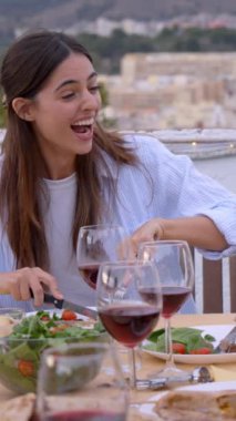 Dikey. Çatıdaki barbekü partisinde etnik çeşitlilikte gençlerin gülümsemesi. Dışarıdaki partiyi kutlayan mutlu bir arkadaş grubu. Erkekler ve kadınlar yaz akşamları neşeyle yer ve içerler..