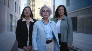 Sadece resmi takım elbiseli, kollarını kavuşturup kameraya bakarak ciddi poz veren olgun beyaz iş kadınlarının portresi. Açık havada güçlü ve başarılı kadın girişimciler.