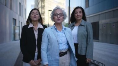 Sadece resmi takım elbiseli, kollarını kavuşturup kameraya bakarak ciddi poz veren olgun beyaz iş kadınlarının portresi. Açık havada güçlü ve başarılı kadın girişimciler.