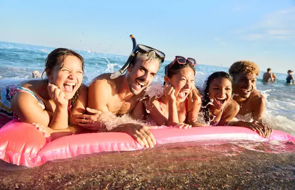 사진을 해변에 팽창식 매트리스에 웃음과 쾌활한 친구의 해변에서 햇볕이 휴가와 스톡 사진