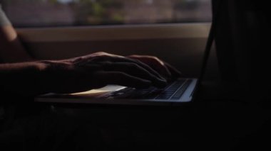 Trenin içinde oturup camdan dizüstü bilgisayar yazan, tanınmayan Kafkasyalı genç elleri kapatın. Z jenerasyonu gölgelerdeki erkek kişi toplu taşıma üzerinde seyahat eden bilgisayarla konsantre oluyor.
