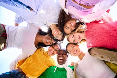 Bir grup çok ırklı gencin düşük açılı görüntüsü. Sadece kameraya bakıp birbirlerine gülümseyen ve sarılan kadınlar. Kadınlar birbirlerine sarılıp eğleniyorlar ve arkadaşlıktan zevk alıyorlar.