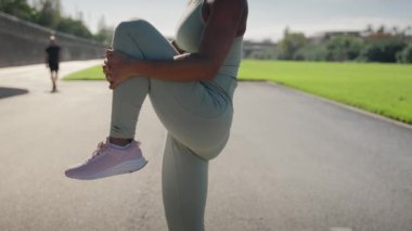 Spor giyim kuşamında spor salonunda spor salonunda koşmadan önce vücut çalışıp ısınan Afrikalı genç bir kadın. Sağlıklı bayan sporcu dışarıda antrenman yapmaktan hoşlanır. Şehirde yaşam tarzı egzersizi