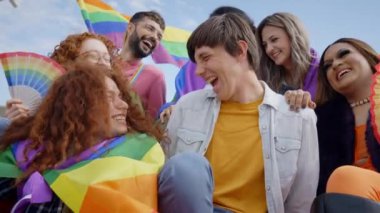 LGBT 'nin çeşitli arkadaşları eşcinseller gününü kutlarken mutlu mesut oturuyorlar. Z neslinin neşeli insanları geçit töreninde eğleniyor. Gökkuşağı bayrakları ve hayranları olan genç liberaller