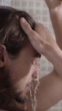 Dikey. Beyaz tenli, uzun saçlı bir erkek evde duş alıyor. Yetişkin Avrupalı sakallı adam banyoda kendini tedavi ederken sırılsıklam oluyor. Sabahları ev içi temizlik kavramı.