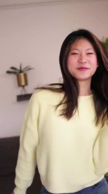 Dikey. Genç Asyalı kız oturma odasında tek başına dans ederken eğleniyor. Sosyal medya için viral dans hareketleri yapan heyecanlı Çinli kadın etkiler. Bekar nesil z insanları evde boş zamanın tadını çıkarıyor. 