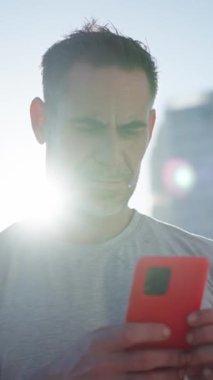 Dikey. Olgun beyaz kaslı adam cep telefonu kullanarak ayakta duruyor. Spor elbiseli bir erkek ciddi bir hücrede kayıyor. Dijital ekrana bağlı sağlıklı insanlar