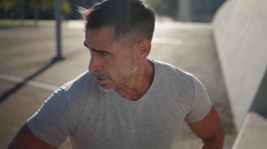 Orta yaşlı beyaz adamın portresi. Koşu yaptıktan sonra dinleniyor ve nefes alıyor. Sağlıklı yetişkin bir erkek şehir bölgesinde koştuktan sonra dinleniyor. Günlük spor rutinlerinde yakışıklı bir sporcu antrenmanı.