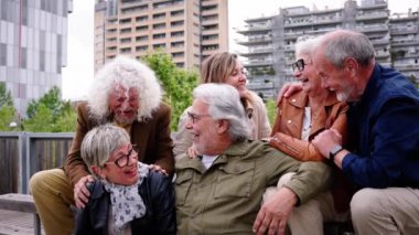 Bir grup yaşlı Kafkasyalı kentteki bankta birlikte gülüyor. Gri saçlı mutlu eski dostlar dışarıda eğlenmek için toplandılar. Neşeli olgun insanların yaşam tarzı güneşli bir sonbahar gününün tadını çıkarıyor.