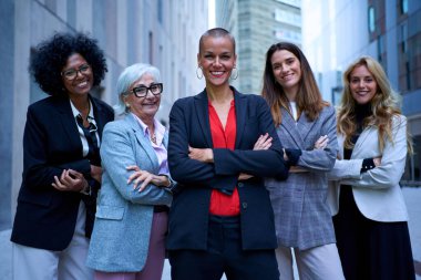 Çok ırklı ve farklı yaşlardaki iş kadınlarının portresi. Resmi takım elbiseli, kollarını kavuşturup kameraya bakan kadınlar. Güçlü ve başarılı bayan girişimciler dışarıda mutlu ve güçlüler.