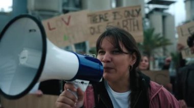 Çevre kirliliği ve fabrikalara karşı düzenlenen bir gösteride, konformist olmayan Z aktivisti kadın elinde megafonla protestolara bağırıyor.