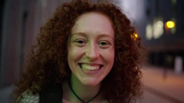 Şehir iş yerinin önünde sırt çantası takan beyaz saçlı genç bir kızın portresi. Gülümseyen ve neşeli bir jest etrafa bakıyor. İlham verici bir atış.