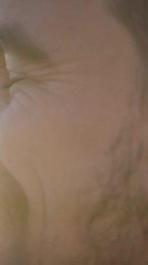 Dikey. Kameraya gülümseyen yakışıklı beyaz adamın yakın portresi. Genç adam dışarıda, pozitif ve rahat bir tavırla anın tadını çıkarıyor. Neşeli milenyum insanları güneşli bir günde.