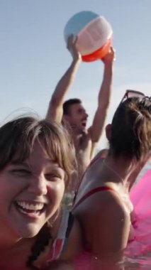 Dikey. Bikinili mutlu kızlar gün batımında denize koşar ve şişme top oynarlar. Neşeli bayan arkadaşlar gölette su sıçratarak eğleniyorlar. Genç kadınlar yüzmeye gider, gölde yıkanırlar. Yavaş çekim