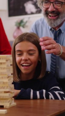 Dikey. Heyecanlı çok nesilli aile toplantısı evde Jenga oynuyor. Beyaz insanlar birlikte oyun oynayarak ev yaşamlarını sürdürüyorlar. Bir kadın kuleden odun parçası alıyor ve düşüyor.