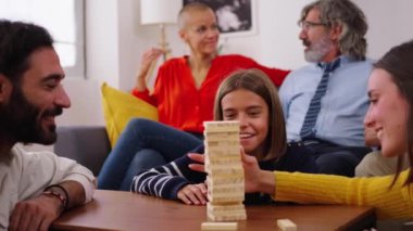 Mutlu nesil aile evde Jenga oynamak için toplandı. Beyaz insanlar birlikte oyun oynayarak ev yaşamlarını sürdürüyorlar. Bir kız kuleden tahta bloğu indiriyor ve diğerleri izliyor.