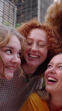 Dikey. Bir grup neşeli genç kız öğrenci selfie portresi çekiyor. Birbirlerine gülümseyen mutlu çok ırklı insanlar. Toplum gençliği yaşam tarzı ve dostluğu. Kendinden emin güçlü kadınlar.
