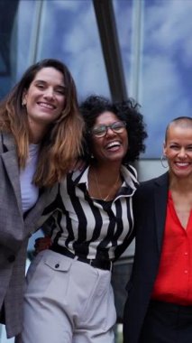 Dikey portre çok ırklı ve çeşitli yaşlarda iş kadınları resmi takım elbiseli, kollarını kavuşturmuş kamerayla gülümsüyor. Güçlü ve başarılı bayan girişimciler dışarıda mutlu ve güçlüler.