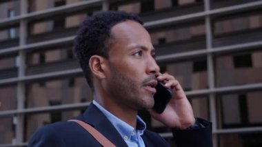 Yakışıklı, yetişkin, Afro-Amerikan iş adamı ofis dışında ciddi bir şekilde cep telefonuyla konuşuyor. Cep telefonu kullanan profesyonel bir giysi. Tatil yapan genç siyahi girişimci.