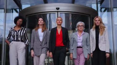 Modern ofis binasının girişinde kameraya doğru yürüyen başarılı ve güçlü iş kadınlarından oluşan alçak açılı bir ekip. Kendine güvenen yetişkin, farklı profesyonel kadın partnerler.