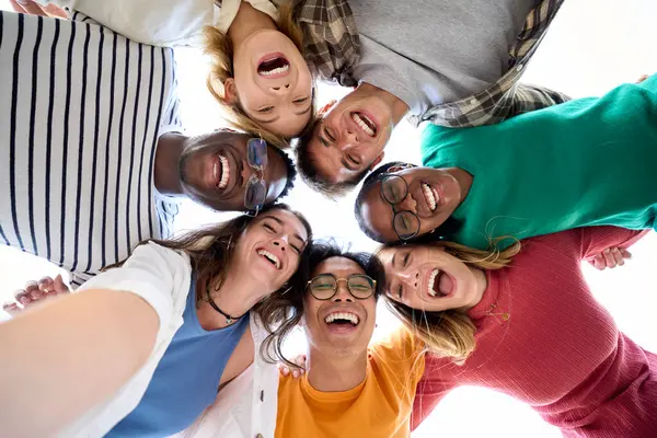 Geniş bir arkadaş grubundan gelen selfie kameraya heyecanlı bir şekilde daire şeklinde sarılmış duruyor. Neşeli genç insanlar dışarıda ayakta durup kucaklaşıyorlar. Z neslinin fotoğrafı güneşli buluşmanın keyfini çıkarıyor.