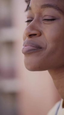 Dikey. Mutlu afro kadın, şehirdeki dairesinin balkonunda sıcak içecek içerek rahatlıyor. Genç siyahi Afrikalı Amerikalı neşeli kız dışarıda eğleniyor. Evdeki ev hayatı