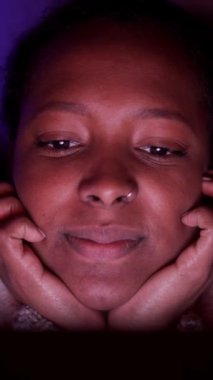 Dikey olarak, genç siyah kızın gülüşünü ve gece evde televizyon seyretmesini. Latin bir kadın, karanlık bir odada uzanmış, gülümsüyor. Yüzü yansıyan bir dizi ya da film izliyor. İnsanlar ev hayatından hoşlanıyor.. 