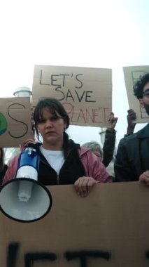 Dikey. Çevre kirliliğini protesto etmek için kameraya bakan bir grup insan. İklim değişikliğini önlemek için düz yüzlü çevreciler savaşıyor. Pro Earth gösteri pankartları