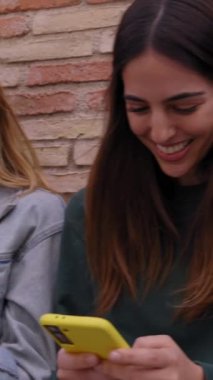 Dikey grup çeşitli mutlu arkadaşlar duvara yaslanmış gülen cep telefonları izliyorlar. Dışarıdaki hücreleri kullanarak bir arada duran gülümseyen nesiller. Teknoloji ve eğlence kavramı