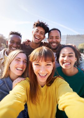 Bir bahar günü dışarıda parti yaparken selfie çektiren bir grup mutlu arkadaş. Bir grup çok kültürlü arkadaş hafta sonları birlikte iyi vakit geçiriyorlar..