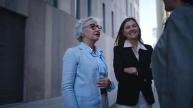 Çeşitli yetişkin iş kadınlarından oluşan bir grup ofis binasının dışında el sıkışarak kendini tanıtıyor. Üç olgun, neşeli profesyonel kadın dışarıda iş hakkında konuşuyor. 