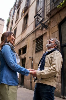 Dikey. Gülümseyen olgun bir çift, şehir sokaklarında el ele tutuşan neşeli emekliler. Kafkasyalı üst düzey emekliler Avrupa tatilinin tadını çıkarıyorlar. Hafta sonu romantik gezisinde mutlu yetişkin partnerler