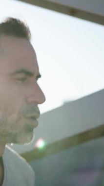 Dikey. Güneşli modern şehir köprüsünde koşan Kafkas erkek yetişkin atlet günlük kardiyo rutini yapıyor. Disiplinli, gri, olgun bir erkek şehirde sağlıklı bir yaşam için dışarıda eğitim görüyor.
