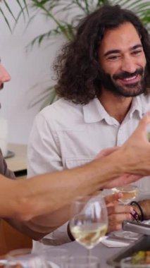 Dikey. Neşeli Kafkasyalı aile, salata kasesinin yanından geçerken canlı bir şekilde masada oturuyorlar. Farklı nesillerden neşeli insanlar ev ortamında birlikte yemek yiyorlar.