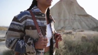 Maceracı Latin Amerikalı güzel kadın Navarra 'daki Bardenas Reales' e sakince bakıyor. Tatil gezintilerinde mutlu bir turist kadın. Doğal çöl bölgesinde yalnız. Açık havada rahat kıyafetler giyiyor.