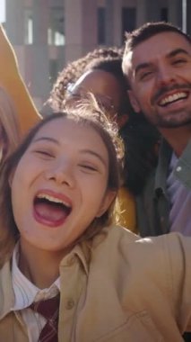 Dikey. Heyecanlı Asyalı genç bir kadın. Neşeli bir grup çok ırklı insan kameraya bakıyor. Mutlu bir toplulukta arkadaşlıklarını kutlarken iyi vakit geçiriyorlar.