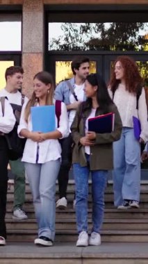 Dikey. Büyük bir grup uluslararası gülümseyen genç öğrenci merdivenlerden inip üniversite binasını terk ediyor ve neşeli bir şekilde konuşuyor. Z neslinin toplumu mutlu insanlar kampüsteki arkadaşlarla ilişkiler