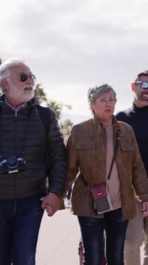 Dikey. Bir grup gülümseyen olgun insan bavullarıyla tasasız bir şekilde Barselona şehrinde tatilin tadını çıkarıyorlar. Çeşitli mutlu orta yaşlı arkadaşlar bahar güneşli günlerinde boş zamanları kutluyorlar.