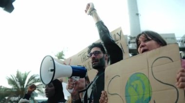 Toplumdaki kirliliği protesto etmek için megafonla bağıran bir adam. Küresel ısınmayı protesto etmek için küresel ısınma pankartlarıyla şikayette bulunan çeşitli gruplar
