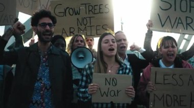 Çeşitli yetişkin insanlar dünyada savaş ve şiddeti protesto ediyor. Barış ve insan hakları gösterilerinde savaş karşıtı pankartlar taşıyan bir grup aktivist yüksek sesle slogan atıyorlar.
