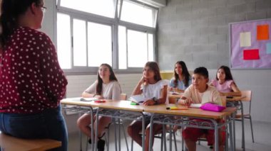 Mutlu grup çeşitli ilkokul öğrencileri sınıfa ellerini kaldırarak katılıyorlar. Heyecanlı İspanyol ergenlik çağındaki çocuklar sınıfta öğretmenlerin sorularına cevap veriyor. İlkokul konsepti