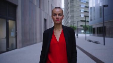 Bir grup başarılı iş kadını dışarıda kameraya doğru güvenle yürüyor. Güçlü ve gururlu kırmızı elbiseli kadın lider ofis binasının yakınındaki kameraya ciddi bir şekilde bakıyor.