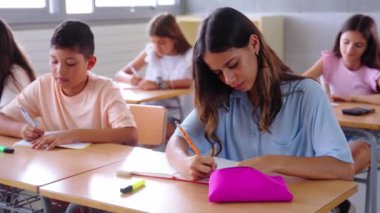 Beyaz kız ilkokul öğrencisi sınıfta öğretmenlik dersi egzersizleri yapıyordu. İnek kız çocuk sınıfta masa başında ders çalışıyor. Ergenlik öncesi çocuklar, ilköğretim kavramı