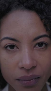 Dikey. Yüzü ciddi bir şekilde orta yaşlı Afro-Amerikan kadın rüzgarlı saçlarıyla kameraya bakıyor. Kendine güvenen afro saçlı kadın dışarıda endişeli bir tavır sergiliyor.