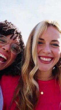 Dikey. Heyecanlı grup, çok ırklı arkadaşlardan oluşan güzel genç bayan topluluğunun kamera turu sırasında kucaklaşıp dışarıda kameraya gülerken eğlenmeleri. Sadece kadınlar ve kızlar bir arada.