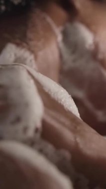 Dikey. Genç Afrikalı kadın duş alırken omuzlarından boynuna kadar sabunlu süngerle kendini temizliyor. Yetişkin afro siyah kadın banyoda günlük hijyen ve vücut bakımı yapıyor. 