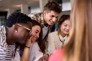 Uluslararası genç dil öğrencileri bir araya gelerek sınıfta oturan bir şeyi arıyorlar. Çeşitli Gen z liseli insanlar İngilizce akademisinde ortak ödev yapmak için toplandı